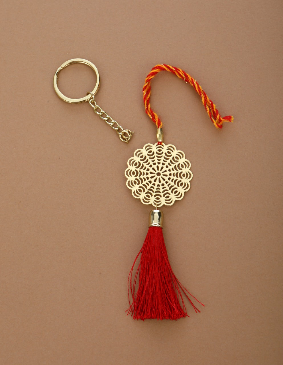 Floral design Rakhi for bhabhi with red hanging tassel cum keychain ring crafted in brass with golden finish
