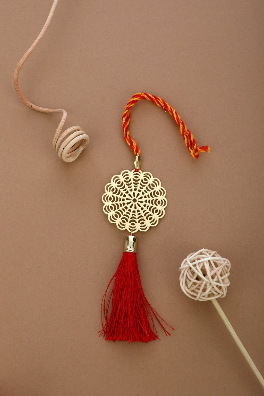 ADORAA's Floral design Rakhi for bhabi with red hanging tassel cum keychain ring crafted in brass with golden finish